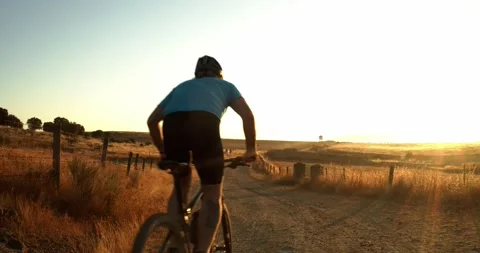 Mountain biker during a sunset on a dirt road Stock Footage 138096212