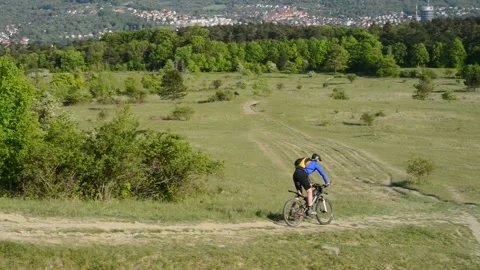 A mountain biker goes down a hill on the horizon the city Jena in Germany Stock Footage 132144569
