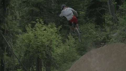 Mountain Biker Going Off Big Jump In Slow Motion View From Behind 库存影片 73499772