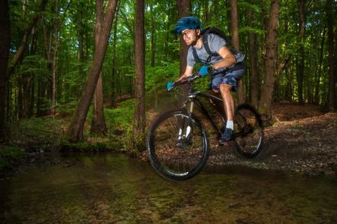 Mountain biker jumping in a puddle in forrest Stock Photos
