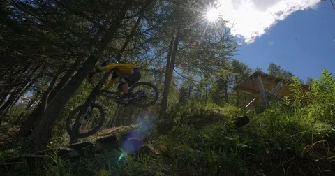 A mountain biker launches of a jump in a forest. Stock Footage