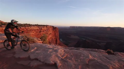 Mountain Biker rides on cliff's edge overlooking beautiful valley Stock Footage 42970875