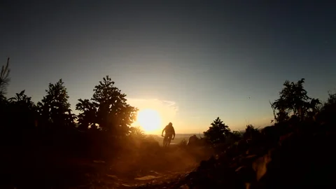 Mountain biker rides past camera into the sunset Stock-Footage 135597706