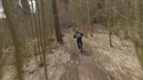 Mountain biker riding challenging forest trail, executing high speed aerial Stock Footage 306397590