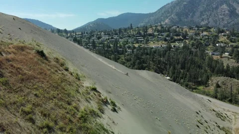 Mountain biker riding down a sand hill, drone shot Stock Footage 289576700