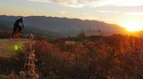 Mountain biker riding off in to the Sunset Stock Footage 68548976