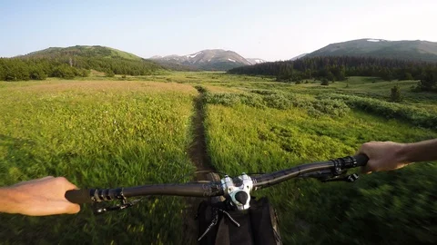 Mountain Biker Riding Through Lush Alpine Valley At Sunset Video stock 102451589