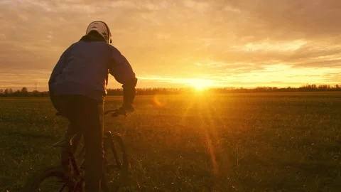 Mountain Biker Riding Through Open Field During Sunset Stock Footage 281815597