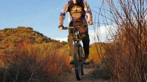 Mountain biker riding through red rocks at sunset Stock Footage 68548960