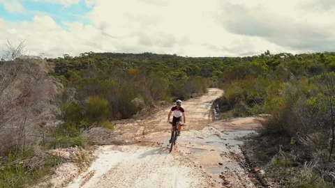 Mountain biker riding toward camera on dirt track Stock Footage 111998028
