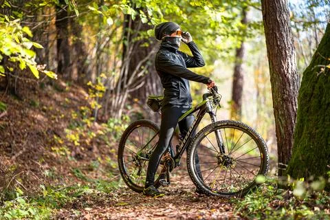 A Mountain Biker Skillfully Riding Through Vibrant Autumn Forest Trails and Stock Photos