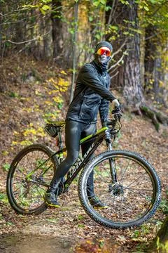 A Mountain Biker Skillfully Riding Through Vibrant Autumn Forest Trails and Stock Photos