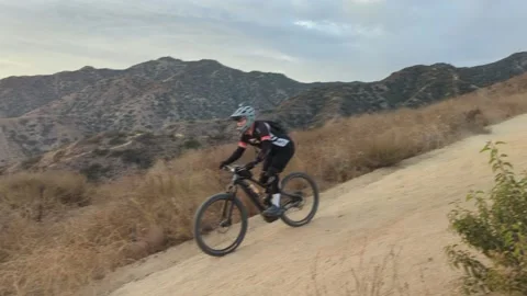 Mountain biker on a steep trail with sunset over Burbank Stock Footage 202592776