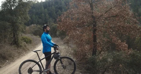 Mountain biker through a forest putting on his helmet Stock Footage 125357091