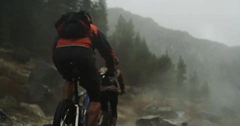Mountain biker tower going over rocks with smoke in background slow motion Stock Footage 64688982