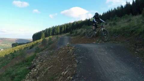 Mountain biker tracked going over large jumps, drone aerial 4K Stock Footage 101107883