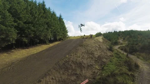 Mountain bikers going over huge jump pulling off huge tricks, drone aerial 4K Stock Footage 101154383