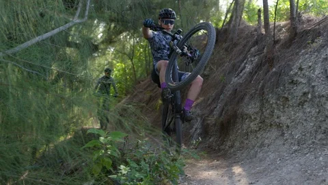 Mountain bikers performing stunts while riding on a woodsy cliff Stock Footage 111419729