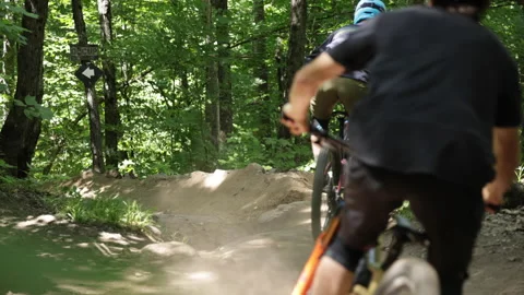 Mountain bikers racing down hill hitting fork in the trail Stock Footage 157325941