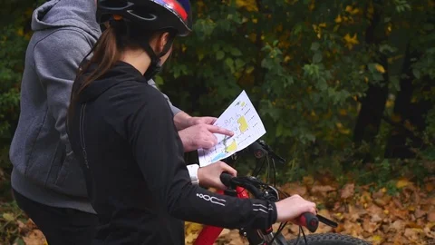 Mountain biking couple looking at map in the forest on a sunny day Stock Footage 82827307
