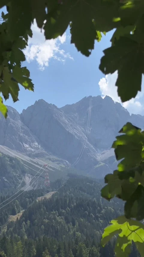 Mountain Cable Car Lines Framed by Forest Leaves Zugspitze Germany highest peak Stock Footage 340543747