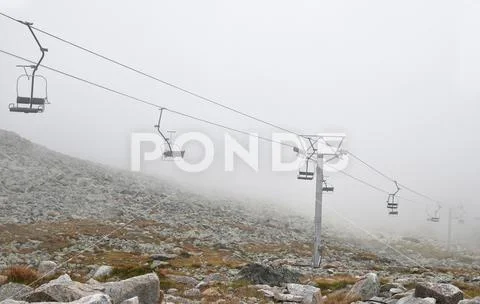 Mountain cableway chairlift in clouds and fog Stock Photos