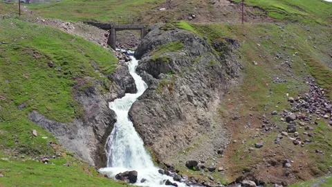 Mountain cascade flows in aerial view through a narrow ravine beside green Stock Footage 340748801