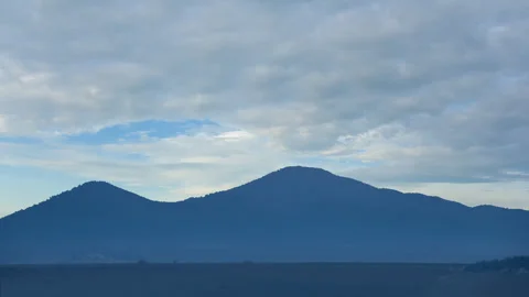 Mountain chain silhouette under a dense cloudy sky Vídeos de archivo 313585680