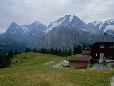 Mountain chalet building by a walking path with dramatic rocky peaks behind Fotos Stock