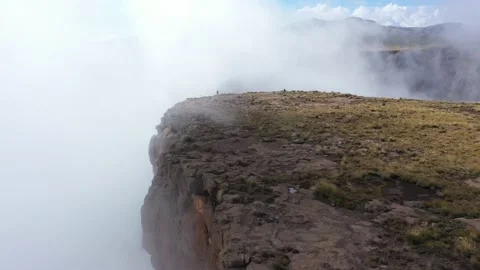 Mountain cliff in clouds with tiny person silhouette 库存影片 221121688
