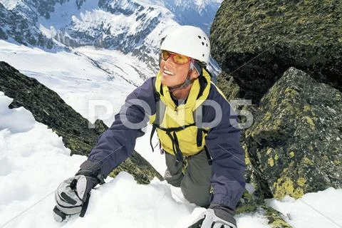 Mountain climber coming up snowy mountain smiling (selective focus) Stock Photos