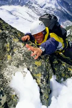 Mountain climber coming up snowy mountain smiling (selective focus) Stock Photos