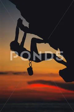 Mountain climber coming up under mountain cliff (silhouette) Stock Photos