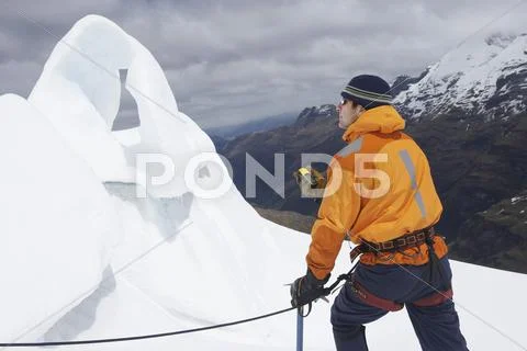 Mountain Climber With Compass By Ice Formation In Mountains Stock Photos