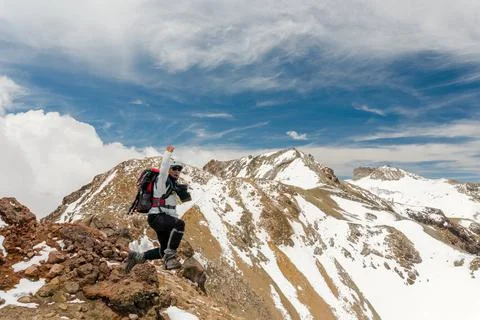 Mountain climber jumping over the summit ridge of a peaks Stock Photos