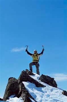 Mountain climber standing on snowy mountain victorious and smiling Stock Photos