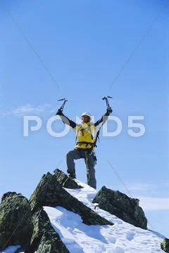 Mountain climber standing on snowy mountain victorious and smiling Stock Photos