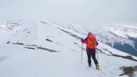 Mountain climber steps carefully into snow on ridge high in mountains. Video stock 255686115