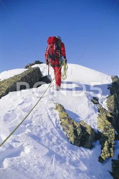 Mountain climber walking on snowy mountain Stock Photos