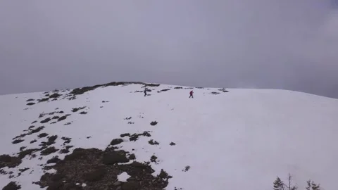Mountain climbers make their way across snowy ridge with dark clouds in Video stock 255708451