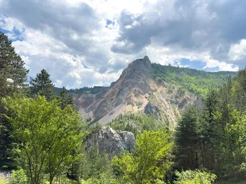 A mountain clothed in trees under a cloudy sky in the backdrop Stock Photos