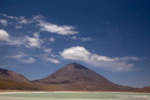 Mountain with a cloud over it on top and a green lagoon. Volcano and lake Stock Photos