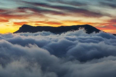 Mountain in the clouds and sunset sky Stock Photos