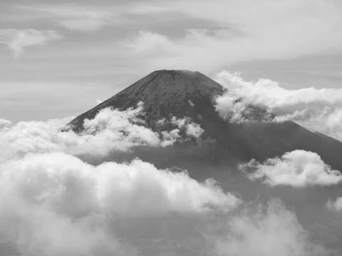 A mountain covered in clouds with a small peak visible Stock Photos