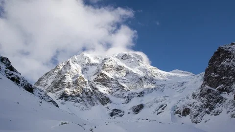 Mountain covered in snow with cloudy blue sky in background during day time Stock Footage 121573573