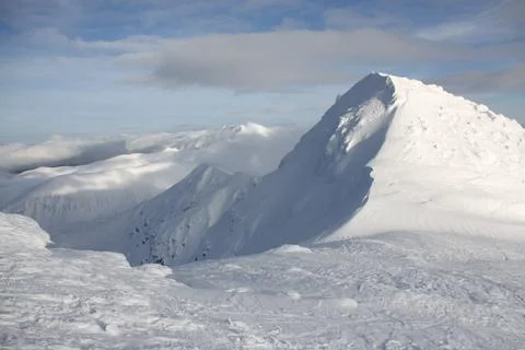 A mountain covered in snow with a cloudy sky in the background Stock Photos