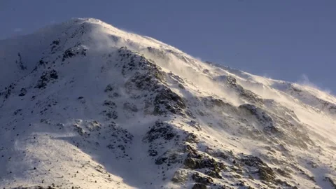 A mountain covered in snow with a strong wind blowing Stock Footage 329479791