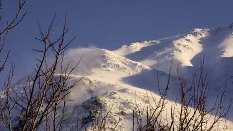 A mountain covered in snow with a strong wind blowing Stock Footage 329479834