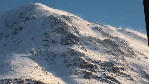 A mountain covered in snow with a strong wind blowing Stock Footage 329479887