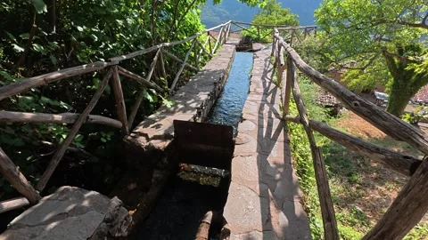 Mountain forest stream falling into cliff beside stone village path Stockbeeldmateriaal 327311785